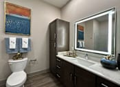 Thumbnail 11 of 28 - A bathroom with a toilet, sink, and a painting on the wall.