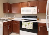 Thumbnail 30 of 42 - Spacious u-shaped kitchen with lots of cabinet space, lots of counter space, porcelain tile floor, and rich brown toned cabinets at The Biltmore Apartments in Omaha, Nebraska