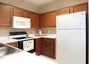 Thumbnail 39 of 42 - Spacious u-shaped kitchen with lots of cabinet space, lots of counter space, porcelain tile floor, and rich brown toned cabinets at The Biltmore Apartments in Omaha, Nebraska