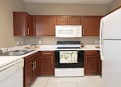 Thumbnail 3 of 42 - Spacious u-shaped kitchen with lots of cabinet space, lots of counter space, porcelain tile floor, and rich brown toned cabinets at The Biltmore Apartments in Omaha, Nebraska