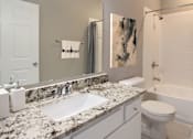 Thumbnail 20 of 35 - Spacious luxury bathroom with white cabinets, granite countertops, gray wall color, porcelain tile floor, soaking tub and tiled shower at Breckenridge Apartments in Omaha, Nebraska