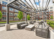 Thumbnail 40 of 62 - Luxury apartments with huge courtyard with modern pergola and seating area, lush landscaping, and green space at Xenia Apartments in Golden Valley Minnesota