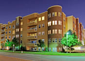 Thumbnail 11 of 28 - A large apartment building with a curved section on the side is lit up at night.