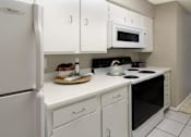 Thumbnail 10 of 10 - Bright white kitchen with gray wall color, white kitchen cabinets, lots of cabinet space, lots of counter space, spacious dining room and porcelain tile floors at The Inverness Apartments in La Vista, Nebraska