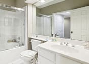 Thumbnail 26 of 73 - Luxury bathroom with white cabinets, cultured marble vanity, and oval soaking tub with glass enclosure at The Saxony Apartments in Dallas