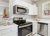 Thumbnail 3 of 73 - Luxury apartments with kitchens with white cabinets and stainless-steel appliances at The Saxony Apartments in Dallas