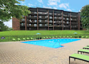 Thumbnail 2 of 41 - Resort-style saltwater pool with huge sun deck, poolside lounge chairs, and park-like setting with lots of trees and scenic views at Embassy Park Apartments in Omaha, Nebraska