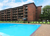Thumbnail 31 of 41 - Resort-style saltwater pool with huge sun deck, poolside lounge chairs, huge balconies, and park-like setting with lots of trees and scenic views at Embassy Park Apartments in Omaha, Nebraska