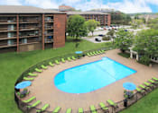 Thumbnail 22 of 41 - Resort-style saltwater pool with huge sun deck, poolside lounge chairs, and park-like setting with lots of trees and scenic views at Embassy Park Apartments in Omaha, Nebraska
