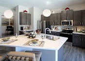 Thumbnail 16 of 28 - A modern kitchen with a white island and grey cabinets.