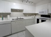 Thumbnail 5 of 43 - A kitchen with white cabinets and a white counter.