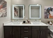 Thumbnail 18 of 28 - A bathroom with two sinks and brown cabinets.
