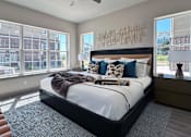 Thumbnail 19 of 28 - A bedroom with a large bed, a ceiling fan, and a view of a cityscape through the windows.