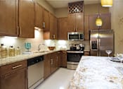 Thumbnail 1 of 42 - Luxury apartments with spacious kitchen and built-in wine rack, granite countertops, kitchen island, stainless steel appliances, and designer tile backsplash at Tuscany Walk Apartments in Houston Texas.