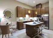 Thumbnail 14 of 42 - Luxury apartments with spacious kitchen and built-in wine rack, granite countertops, kitchen island, stainless steel appliances, and designer tile backsplash at Tuscany Walk Apartments in Houston Texas.