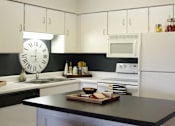 Thumbnail 35 of 41 - Kitchen with white cabinets, lots of cabinet space, kitchen island, prep island, and colored feature wall at Embassy Park Apartments in Omaha, Nebraska
