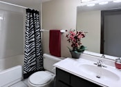 Thumbnail 13 of 27 - Bathroom with black cabinets, tiled floor, and tiled shower with tub at Kensington Woods Apartments in Omaha Nebraska