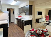 Thumbnail 14 of 27 - Spacious living room, dining room and kitchen with wood laminate flooring, black cabinets and white countertops at Kensington Woods Apartments
