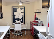 Thumbnail 3 of 27 - Fully equipped kitchen with black cabinets, ample countertop space, wood laminate flooring, and dining area at Kensington Woods Apartments