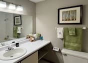 Thumbnail 15 of 35 - Bathroom with tiled shower, tiled floors, lots of cabinet space, and extra storage space at LionsHead Apartments in Omaha Nebraska