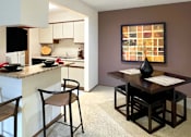 Thumbnail 29 of 35 - Dining room area with painted feature wall, granite breakfast bar, and kitchen with tiled floor at LionsHead Apartments in Omaha Nebraska