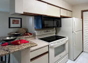 Thumbnail 11 of 35 - Kitchen with glass top stove, separate laundry room, tile floors, and granite breakfast bar at LionsHead Apartments in Omaha Nebraska