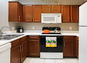 Thumbnail 20 of 36 - Luxury apartments with honey brown cabinets, tiled floors, white countertops, and u-shaped kitchen at Lenox Village Apartments in Lincoln, Nebraska