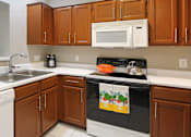 Thumbnail 13 of 36 - Luxury apartments with honey brown cabinets, tiled floors, white countertops, and u-shaped kitchen at Lenox Village Apartments in Lincoln, Nebraska