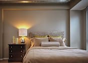 Thumbnail 3 of 41 - A bedroom with a bed, nightstand, and lamp.