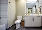 Thumbnail 6 of 41 - A white toilet sits in a bathroom next to a white bathtub.