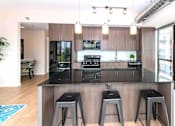 Thumbnail 8 of 41 - A modern kitchen with a black countertop and bar stools.