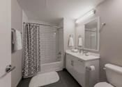 Thumbnail 9 of 41 - A white bathroom with a shower curtain and a white tub.