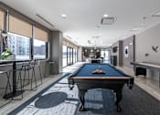 Thumbnail 11 of 41 - A pool table is in the middle of a room with a long table and chairs.