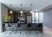 Thumbnail 32 of 41 - A modern kitchen with a bar area and chairs.