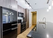 Thumbnail 39 of 41 - A modern kitchen with a black countertop and stainless steel appliances.