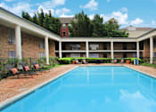 Thumbnail 9 of 19 - Apartments near the Galleria with multiple swimming pools, sun deck with poolside lounge chairs, brick exteriors and courtyard setting at Plantation apartments in Houston.