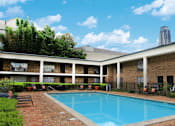 Thumbnail 1 of 19 - Apartments near the Galleria with multiple swimming pools, sun deck with poolside lounge chairs, brick exteriors and courtyard setting at Plantation apartments in Houston.