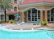 Thumbnail 12 of 28 - Luxury apartments with resort-style pool with fountains, pool-side lounge chairs, spa, and palm trees at Tuscany Court Apartments in Houston.