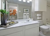 Thumbnail 15 of 30 - Spacious bathroom with white cabinets and white porcelain tile at Preston Village Apartments in North Dallas