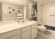 Thumbnail 8 of 30 - Spacious bathroom with white cabinets and white porcelain tile at Preston Village Apartments in North Dallas