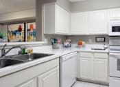 Thumbnail 3 of 30 - Bright white kitchen with tile floors at Preston Village Apartments in north Dallas