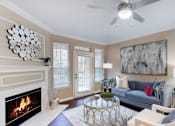 Thumbnail 8 of 20 - Spacious living room with wood-burning fireplace with glass doors, ceiling fan, French door, at Tuscany Gate Apartments in Houston.