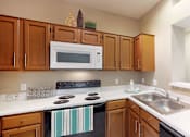 Thumbnail 5 of 20 - A kitchen with wooden cabinets and a black stove top oven.