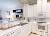 Thumbnail 5 of 26 - Luxury apartments with white cabinets, bright white kitchens, granite breakfast bar, and side-by-side refrigerator at RidgeGate Apartments in Minnetonka, Minnesota