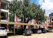 Thumbnail 7 of 17 - Covered car ports and red brick exteriors at Tuscany Lane Apartments in Houston.