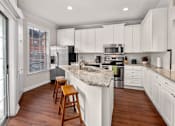 Thumbnail 17 of 26 - Spacious kitchen with island, granite countertops, custom home cabinets, smooth glass top stove, spacious pantries, and stainless-steel appliances at Tuscany Villas in Houston.