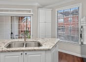 Thumbnail 22 of 26 - Spacious kitchen with island, granite countertops, custom home cabinets, French doors, smooth glass top stove, spacious pantries, and stainless-steel appliances at Tuscany Villas in Houston.