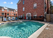 Thumbnail 5 of 34 - Luxury townhomes with swimming pool and poolside lounge seating at Tuscany Row in Houston.