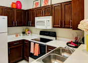 Thumbnail 17 of 36 - Spacious kitchen with honey brown toned cabinets with modern silver hardware, and white appliances