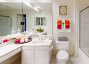 Thumbnail 9 of 36 - Spacious bathroom with oval soaking tub with glass enclosure, cultured marble vanity, glass shower, and built-in vanity at Tuscany Apartments in Houston.